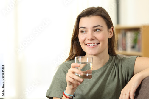 Teen holding a water glass looking at side at home