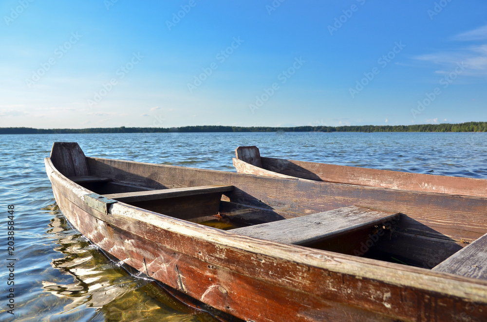 Old wooden fishing boats on the lake beach with blue sky.