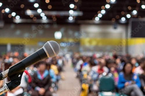 Microphone over the Abstract blurred photo of conference hall or seminar room in Exhibition Center background with Speakers on the stage and attendee background, Business meeting and education concept