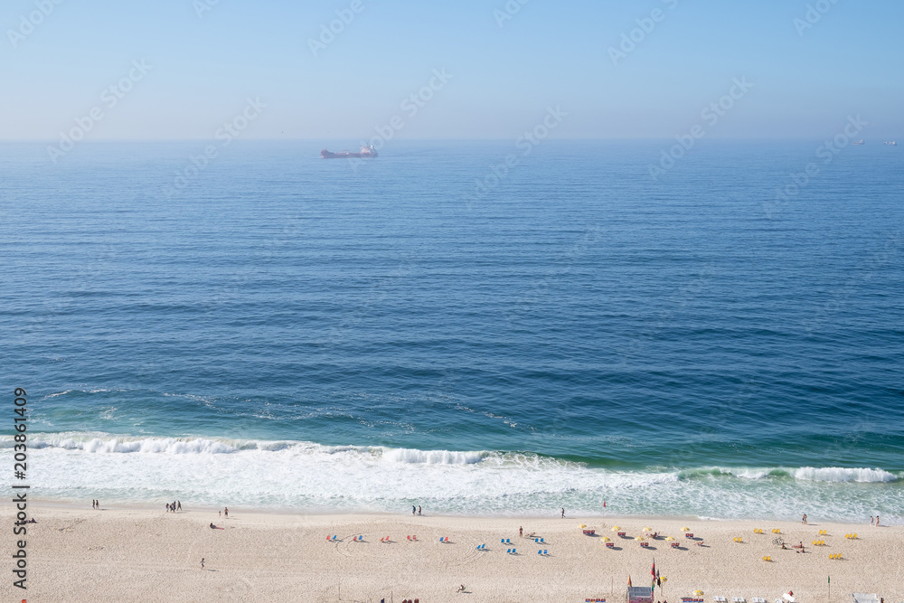 view of Copacabana beach during early morning, taken from the rooftop of a hotel, some slight fog can be seen on the blue sky. Rio de Janeiro, Brazil