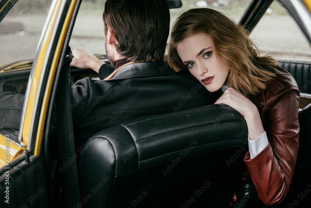 beautiful young woman looking at camera while boyfriend driving car