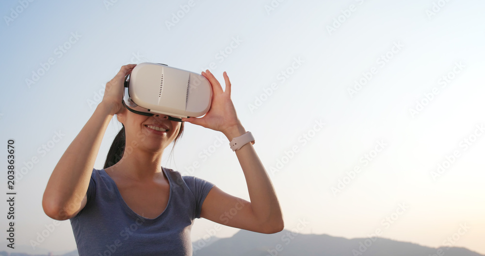 Woman playing with VR device at sunset time
