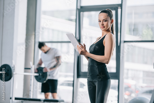 young female trainer with digital tablet and athletic man with barbell at gym Free Download young female trainer with digital tablet and athletic man with barbell at gym - GFXLoad