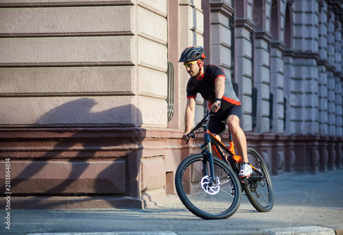 Bicyclist in professional cycling clothing and protective helmet riding bicycle along old historical city streets, taking turns, performing tricks in urban area