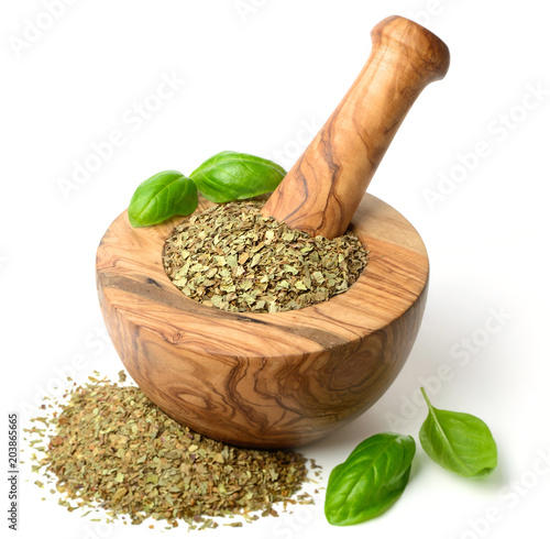 dried herb, basil leaves in the wooden mortar, isolated on white