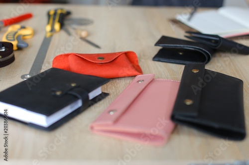 Handmade leather wallets and notebook on table at atelier. Concept of home business, handicraft and hobby. photo