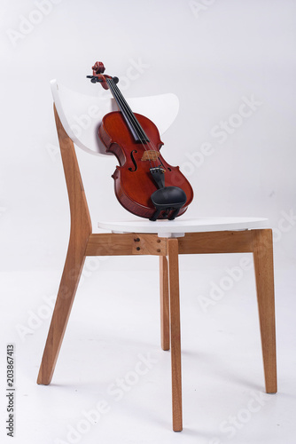 The classic violin put on wooden chair,on white bckground.