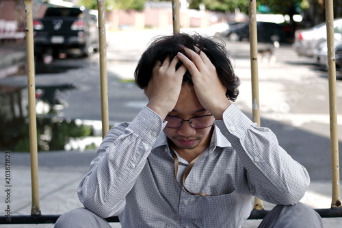 Confused anxiety young Asian business man covering face with hands. He is feeling disappionted or exhausted. © tuaindeed