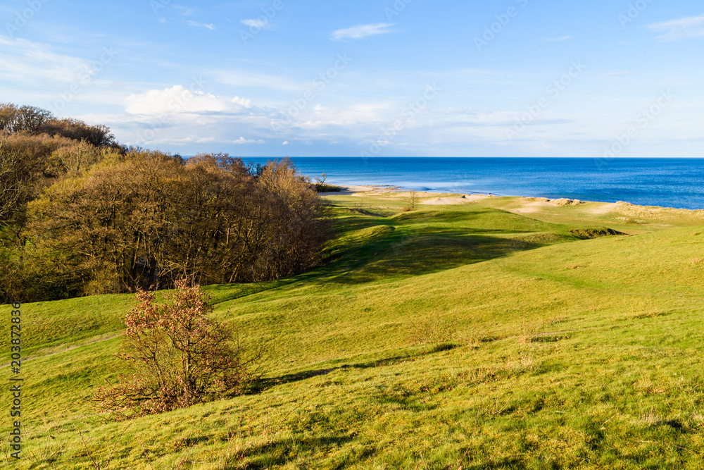 Havang, Sweden. Landscape view over grass covered sand dunes with the Baltic sea in the background on a sunny spring evening.