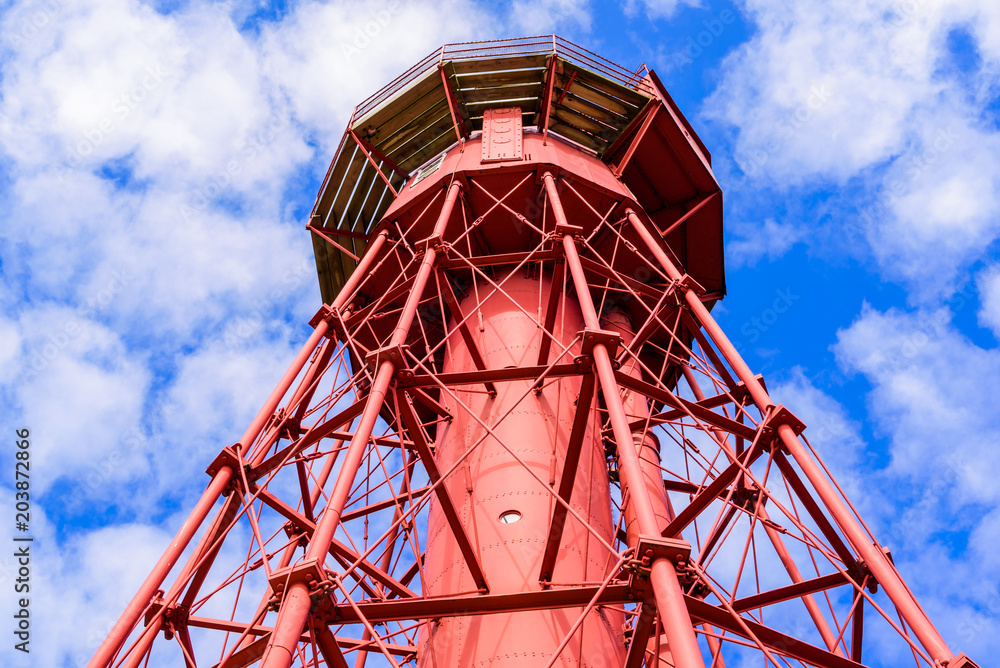 Sandhammaren, Sweden - Close up of the lighthouse and its framework. Blue sky with white clouds in the background. Sandhammaren, Sweden - Close up of the lighthouse and its framework. Blue sky with white clouds in the background.