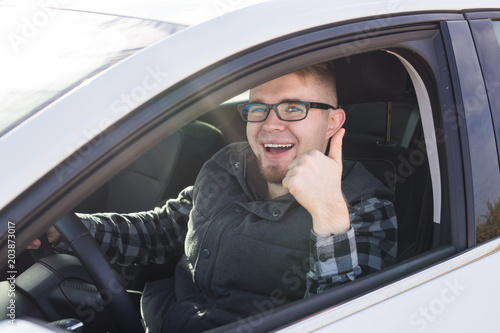 Εκτύπωση καμβά Cheerful casual guy smiling happily showing thumbs up sitting in a big white car