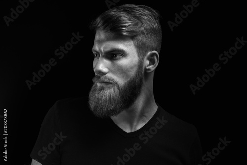 Black and white studio shot of confidence attractive hipster Dramatic light concept Black background Copy space Bearded man