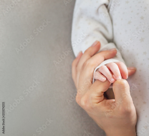 Mom keeps his newborn baby by the hand  family love caring concept