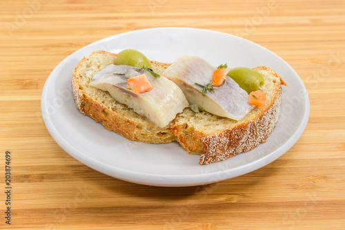 Open sandwich with pickled herring, olives, brown sprouted bread closeup