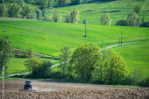 Tractor plowing field and beautiful landscape, France