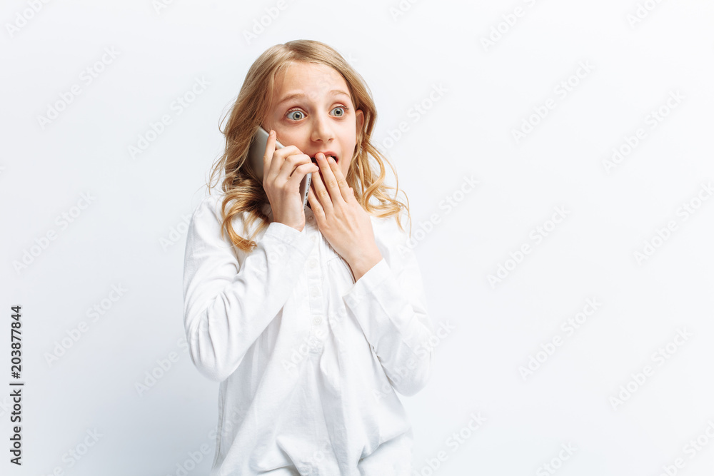 Beautiful teen girl talking on mobile phone, the girl in shock from the news, photo Studio, isolated Beautiful teen girl talking on mobile phone, the girl in shock from the news, photo Studio, isolated