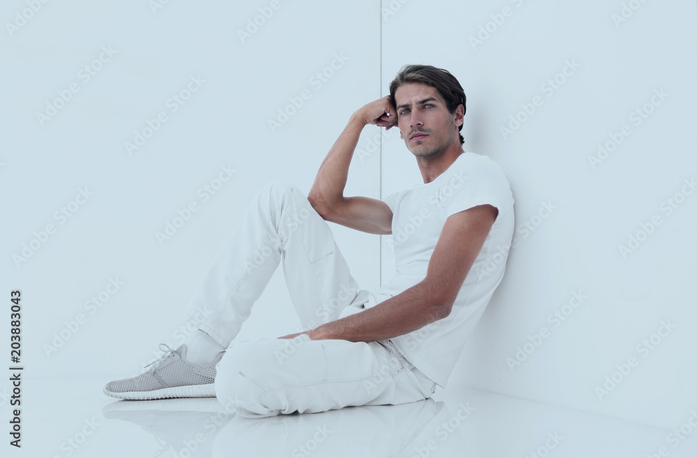 anxious man sitting beside a white wall