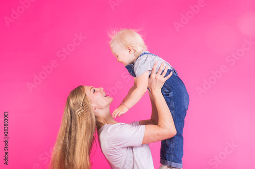 happy little girl and her mother having fun over pink background
