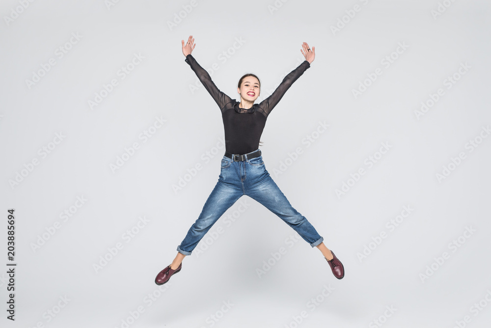 happiness, freedom, power, motion and people concept - smiling young woman jumping in air with raised fists over white background