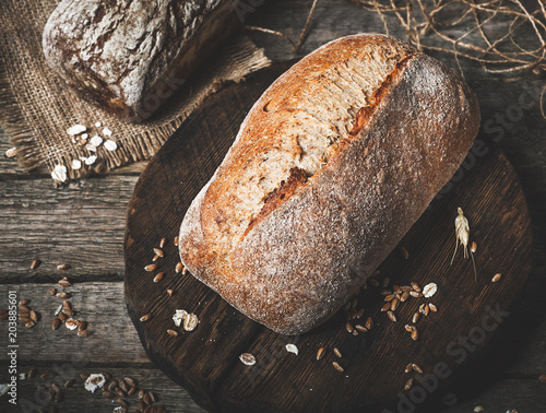 Rustic bread and wheat on an old vintage planked wood table. Dark moody background with free text space.