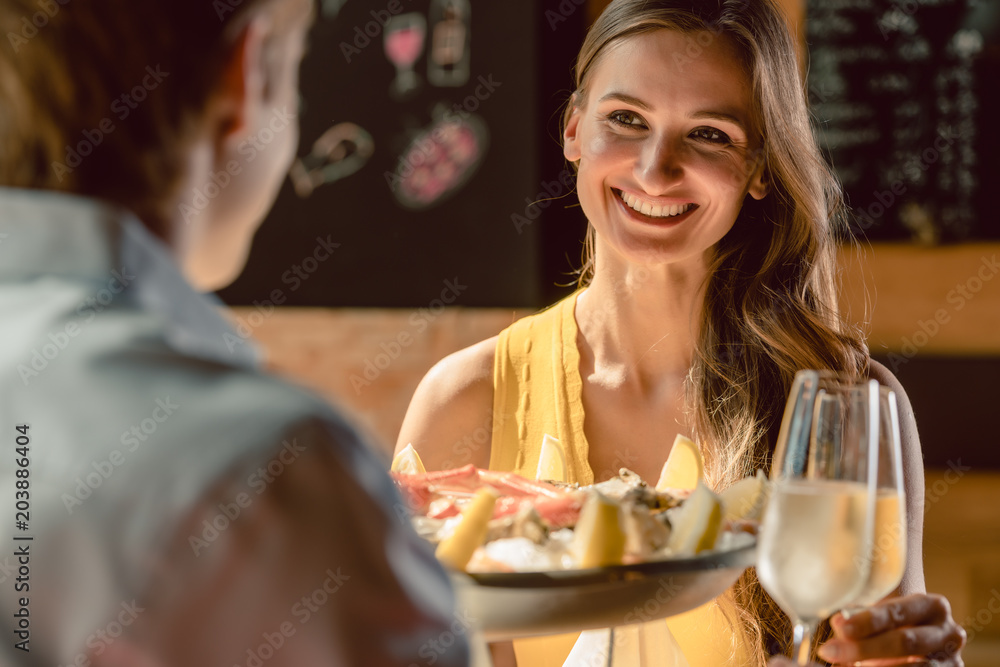 Happy young couple in love toasting with champagne during romantic dinner with seafood as oysters and crabs at the restaurant