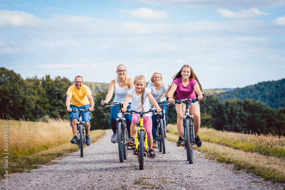 Fototapeta Family riding their bicycles on afternoon in the summer countryside