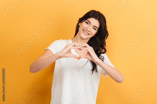 Beautiful young lady showing heart love gesture.