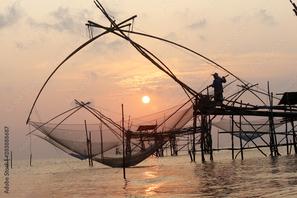 The fisherman work wit his net in the early morning.