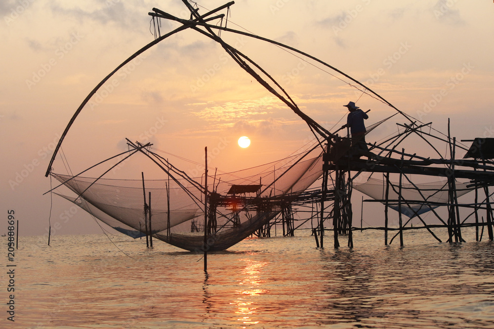 The fisherman work wit his net in the early morning.