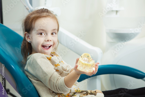 Child plays with artificial human jaw in dentist chair