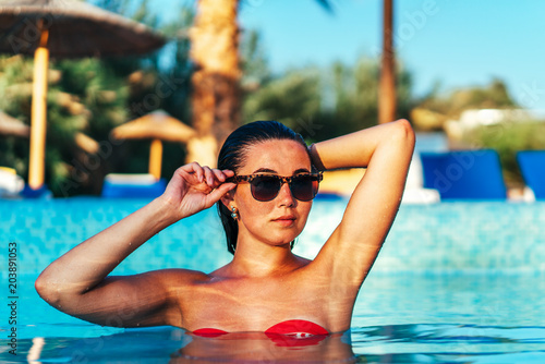Pretty brunette girl relaxing at the swimming pool