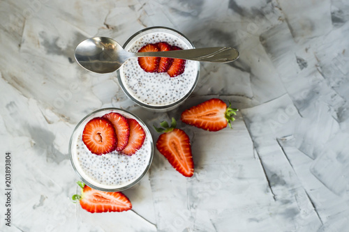 Two servings of dessert made of chia seeds, milk and strawberries on a gray table. Healthy Breakfast Concept. Top view