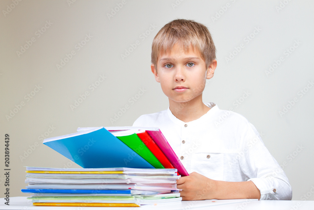 Child with colorful books, notebooks and school textbooks doing his homework at home. Child with colorful books, notebooks and school textbooks doing his homework at home.