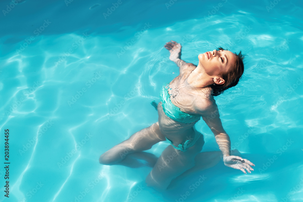 Beautiful young woman floating in pool