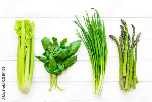 Green fresh herbs and vegetables on white wooden background. Flat lay, eco vegan background