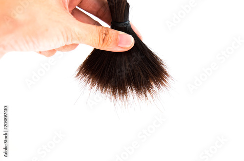 Hand holding cut off hair on white background