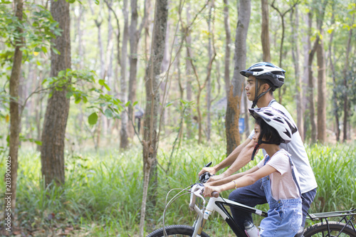 Happy father and daughter cycling in the park, togetherness relaxation concept