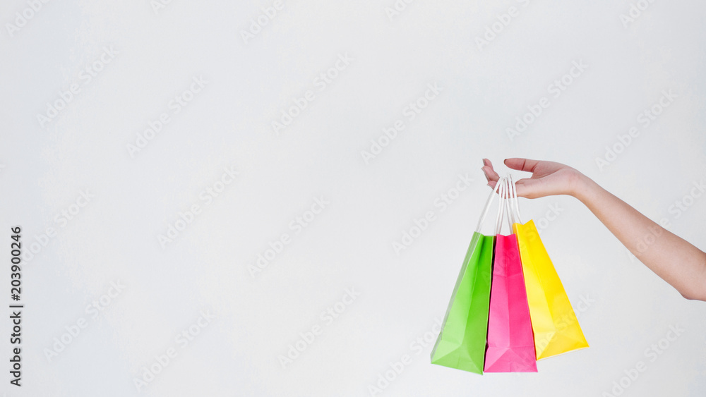 hand of woman holding colorful shopping bags with copy space