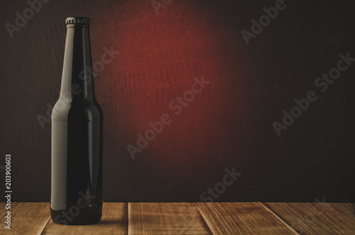 black beer bottle with red light background/black beer bottle with red light background. Selective focus and copyspace