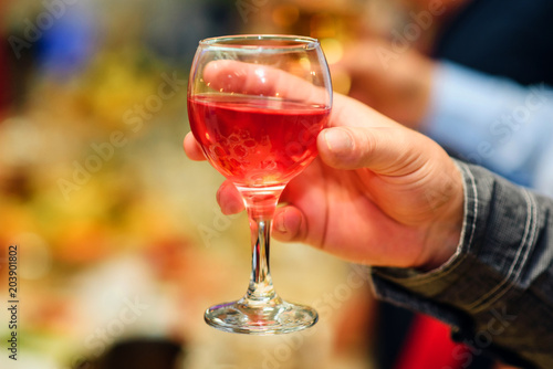 hand of a man with a glass of red wine closeup with blurred background