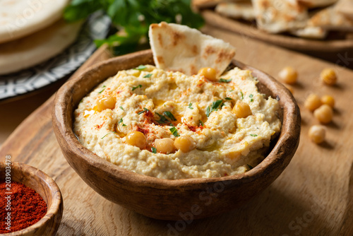 Homemade chickpea hummus bowl with pita chips and paprika. Closeup view, selective focus