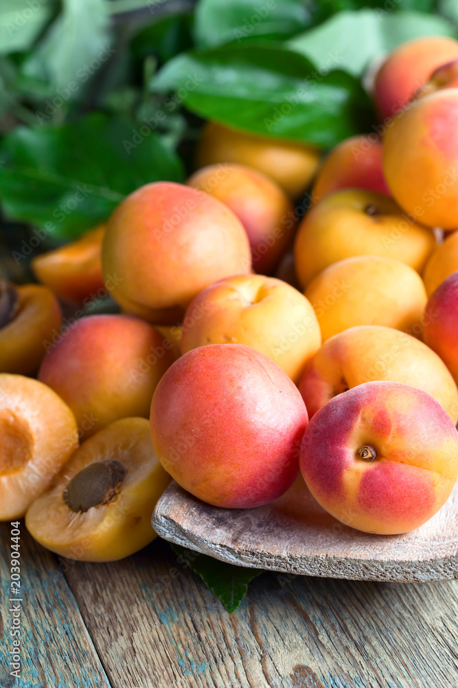 Apricots with leaves on old wooden table . Apricots with leaves on old wooden table .