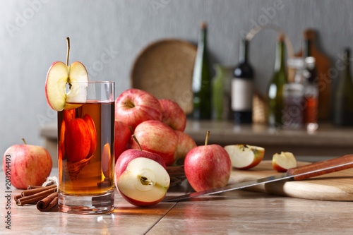 Glass of apple juice and ripe pink apples on a kitchen table