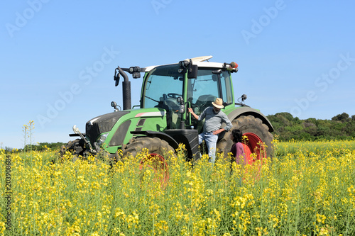 couple of farmers in a canola field with a tractor