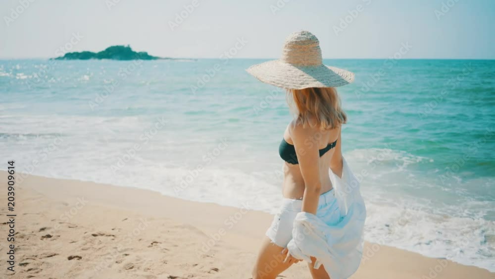 Woman walking on the ocean beach under blue sky in sunny day. Seascape view with palms. Woman walking on the ocean beach under blue sky in sunny day. Seascape view with palms.