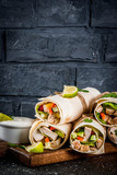 Healthy lunch snack. Stack of mexican street food fajita tortilla wraps with grilled buffalo chicken fillet and fresh vegetables, dark background copy space