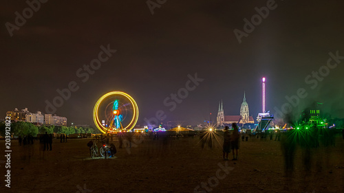 Nachts auf der Münchner Frühlingswiesn, ein bleuchtetes Riesenrad und die St. Pauls Kirche im Hintergrund photo