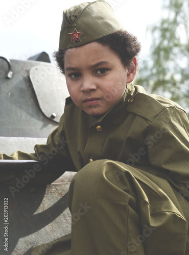 Boy in the military uniform on the tank of time of Second World War. Kids in uniform. Soldier boy. War time. photo