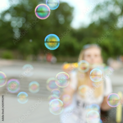 Blurred background with shallow depth of field. The girl lets the soap bubbles in the park, has a fun weekend.