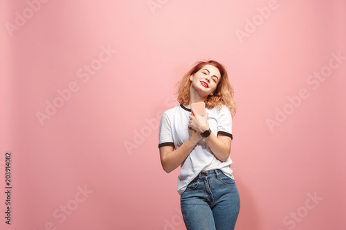 The happy business woman is smiling and keeping in hand the smartphone against pink background.